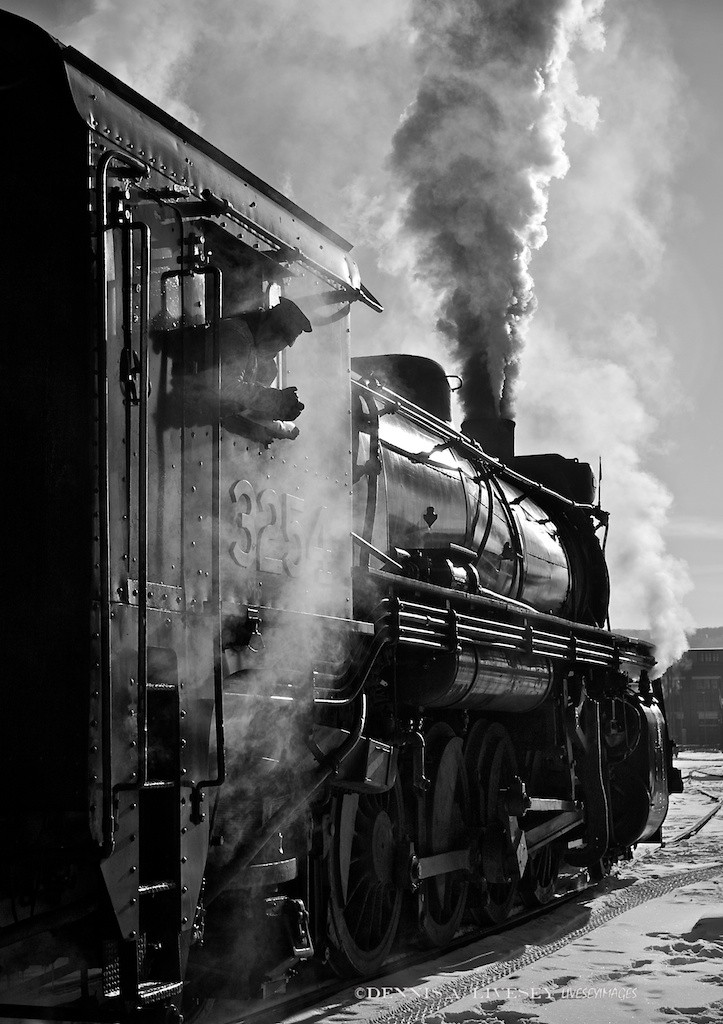 On January 17th, 2009, I took this image of Steamtown’s CN No. 3254. The temp was around 10F, fairly new snow was on the ground and, most astonishingly, the sky was clear. Being winter, the sun was low and with the clear sky and snow, the light was utterly amazing for Scranton! I kept finding these exciting shots looking into the sun. The front lit was good, don’t get me wrong, but the back lit stuff had my fun meter pinned. I think Gordon Willis would approve for not only can’t you see engineer Aaron Stout’s eyes, you can’t see his face! The light, the steam, the vapor, the black engine and the white snow are so contrasty, I even like to think Conrad Hall would smile.