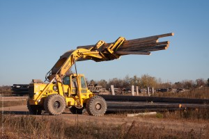 A heavy equipment operator grabs a stack of wood poles to be moved to the drying facility. This is Bell Lumber and Pole Company's Barron pole yard facility. The company was established in 1909 in northern Wisconsin. The company has grown throughout North America since then. This particular pole yard was served by the Wisconsin Northern until Canadian National took back over operations on the Barron Sub.