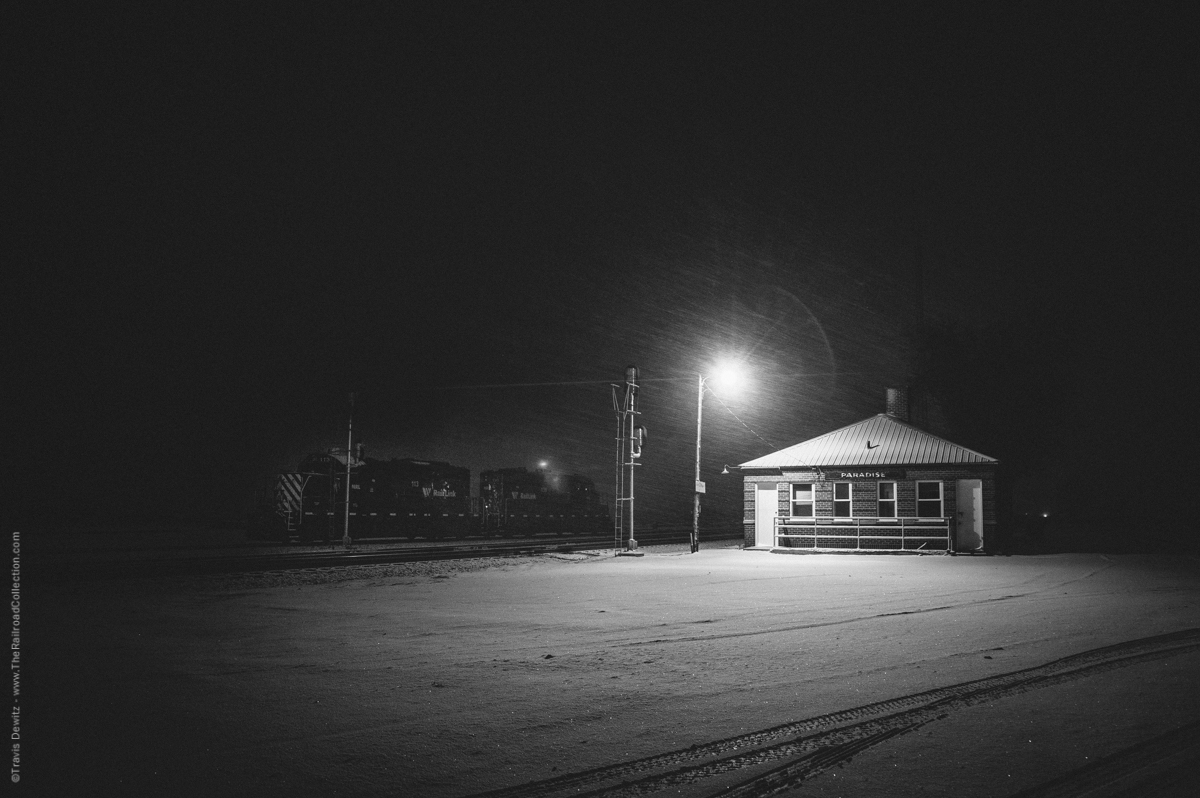 A place where it all comes together, Paradise, Montana. It is March, 2015, a strong wind whips the falling snow throughout western Montana including in Paradise. Two Montana Rail Link geeps sit in the yard next to the old depot. These locomotives are used for the Paradise local that serves the area.  The tracks were first laid here in 1883 by the Northern Pacific Railway. That same year, Paradise was born. Many argue that the name originally was “Pair o’ Dice” but not by the railroads accounts. This was NP’s division point and also where crews would set their watches forward or back to compensate for the time zone change (Mountain-Pacific) on their mainline to the west coast.  The Northern Pacific Railway also operated a tie treating plant here where timber ties were creosoted. The plant was destroyed by fire. Paradise is wedged between the Coeur d'Alene Range to the south and Cabinet Range to the north along with the Clark Fork. The second highest peak of the  Coeur d'Alene Range towers over Paradise, Patricks Knob(6,837 feet). Just to the east is where the Flathead River meets the Clark Fork. At this junction, the   Reservation Divide comes to a point with the other two ranges creating tripoint. These three ranges protect the 2,500 foot lower valley of the Clark Fork River, which has mild winter weather comparable to the Pacific maritime. Plains, MT just west of Paradise was once called Wild Horse Plains. Native American use to winter there horses there. Paradise is also where the MRL’s 10th Subdivisions meets the 4th Subdivision. The 10th Sub was Northern Pacific’s original route west from Missoula. It followed along what was once an Indian Trail and later a wagon trail up Evaro Hill to the Clark Fork. The grade up Evaro hill is 2.2% in both directions which made for a tough climb. In 1909, NP finished the low line that ran along the Clark Fork. The low line or river line is 20 miles longer and is the route mainly used west from Missoula. The line up