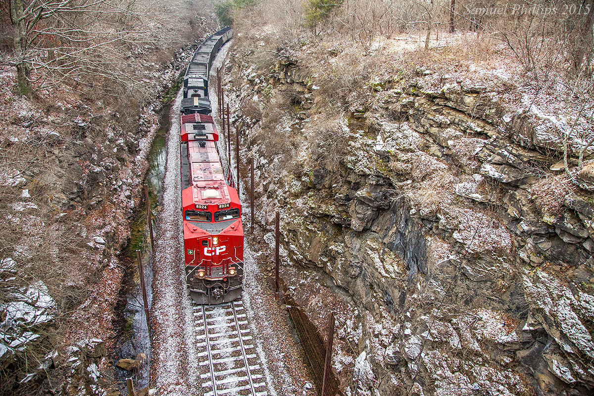 In a beautiful winter scene, train 811 roars upgrade through the deep rock cut at Oney Gap with a visiting Canadian Pacific ES44AC leading the way to Elmore. The train is down to a crawl as the locomotives slip on the snow and ice slickened rail while ascending the 1.5% grade.